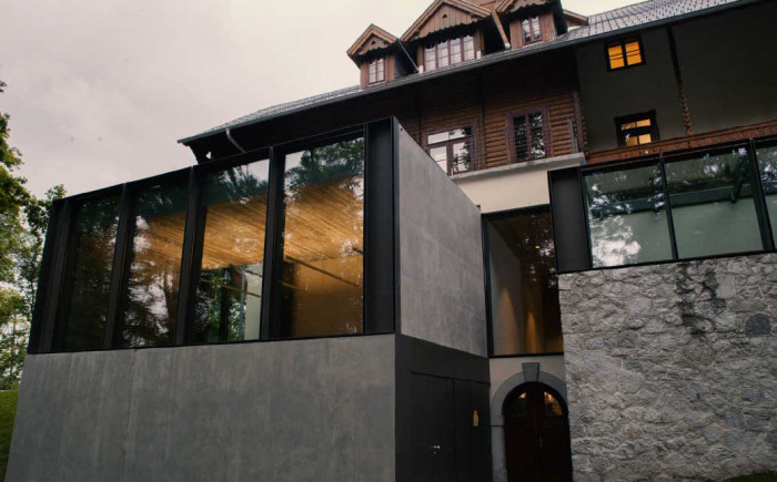 Front of a building, in wood and stone, before a grey sky - the MGLC Švicarija.