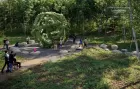 A giant grassy geodesic shape sits in the middle of a circle of stones. People admire it from outside.