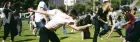 A large group of young people are dancing in a park - none of it synced, all kinds of postures.