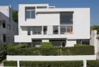 A very architect-y white building, boxy and with big windows.