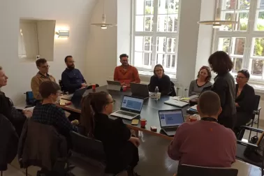 A dozen or so people sitting around a conference table at a presentation on digital mobility.