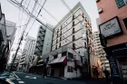 A street in Matsudo, Japan - mid-size tower blocks at either side of the road and lots of cabling overhead. 