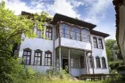 A wooden building with timber struts framing panels painted eggshell blue and decorated with fancy patterns.