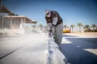 Wearing safety goggles and a mask, a man uses a power tool to cut into the bed of stone he is sculpting.