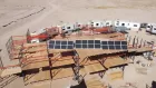 Three large solar panels arranged on a pallette-rack structure in the desert.