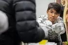 A gloved student holds out a pipette filled with a blueish liquid in a laboratory setting.